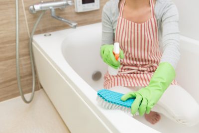 手袋をつけてお風呂掃除をしている主婦